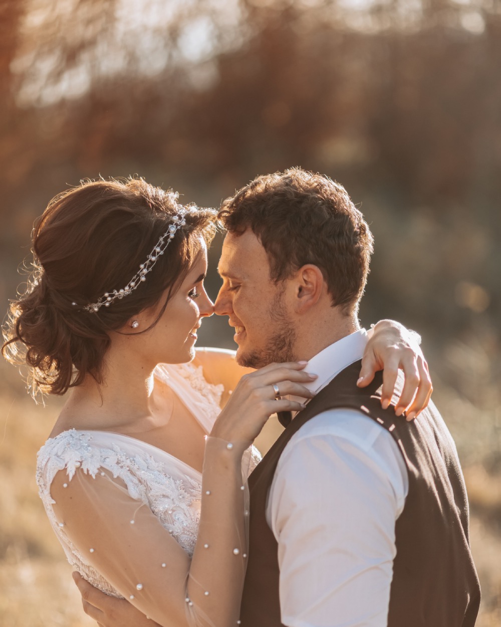 Bride and groom embrace in golden sunlight during romantic outdoor wedding portrait at Borealis Bison Barns