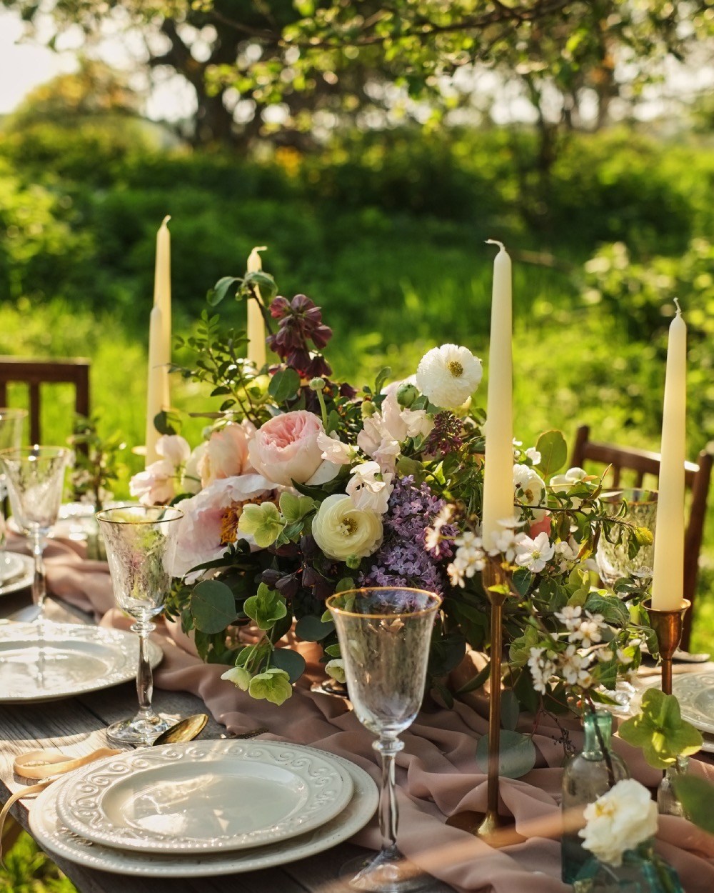 Garden-inspired wedding tablescape with candles, flowers, and vintage glassware at Borealis Bison Barns venue.