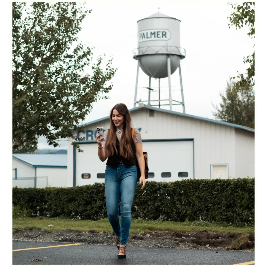 Woman walking near Palmer Alaska water tower while looking at phone