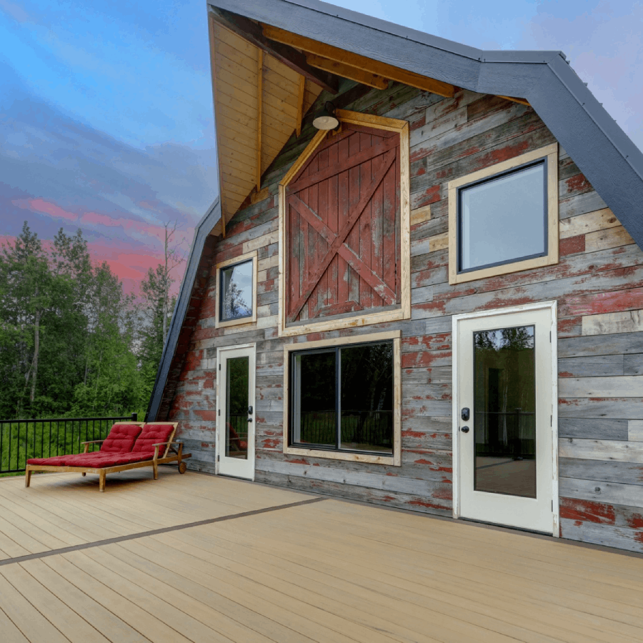 Wraparound deck at Borealis Bison Barns featuring restored barn wood siding, historic barn doors, outdoor seating, and scenic Alaska views.